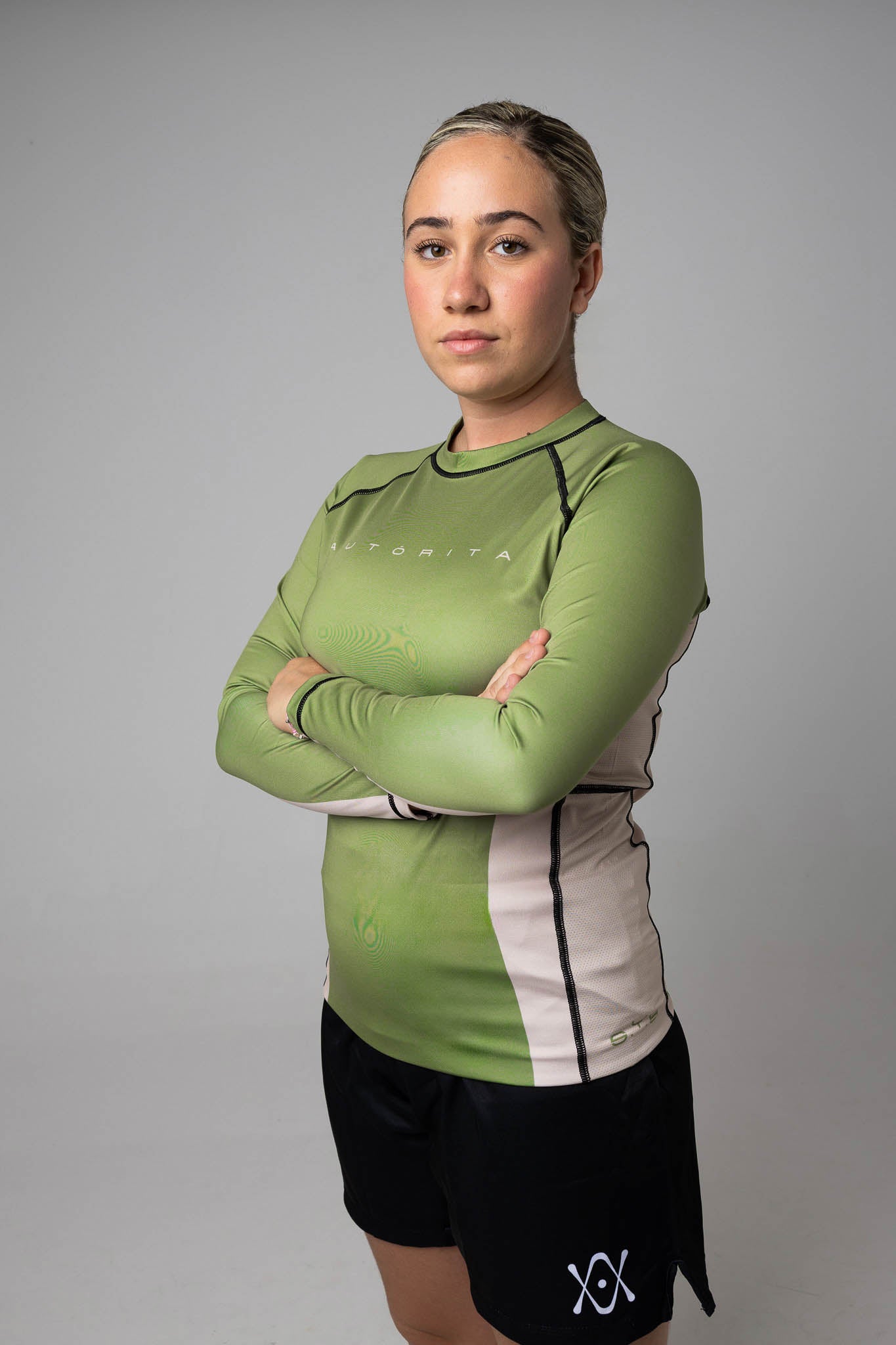 Mujer con los brazos cruzados mostrando el panel lateral de la rashguard de manga larga