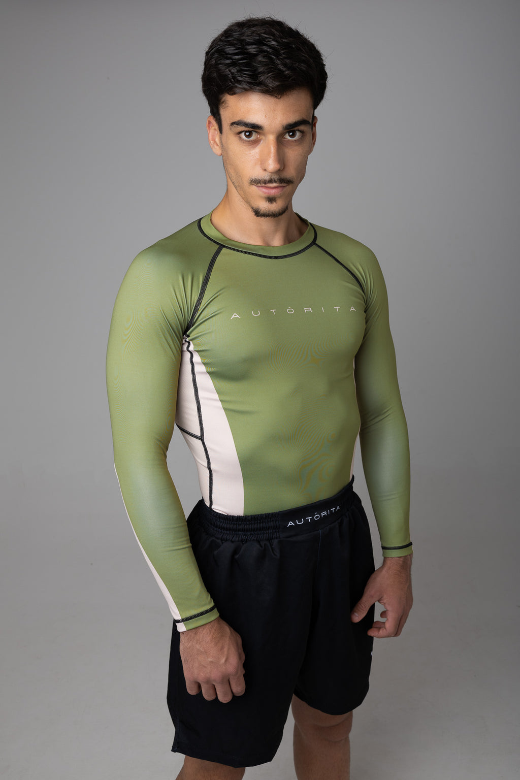 Hombre mostrando el ajuste de la rashguard verde anti-pilling para grappling y BJJ