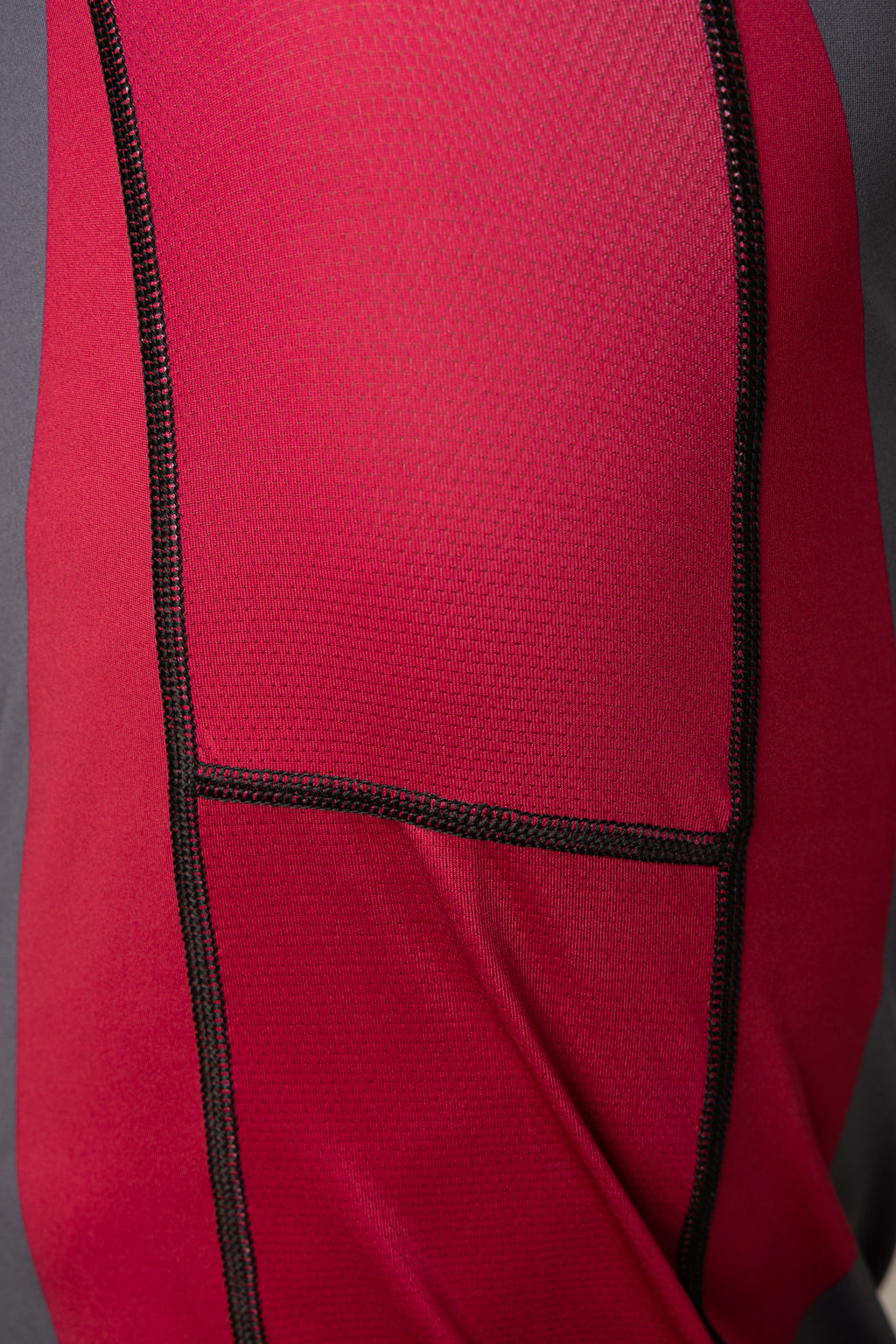 Detalle del panel granate y las costuras reforzadas de la rashguard gris