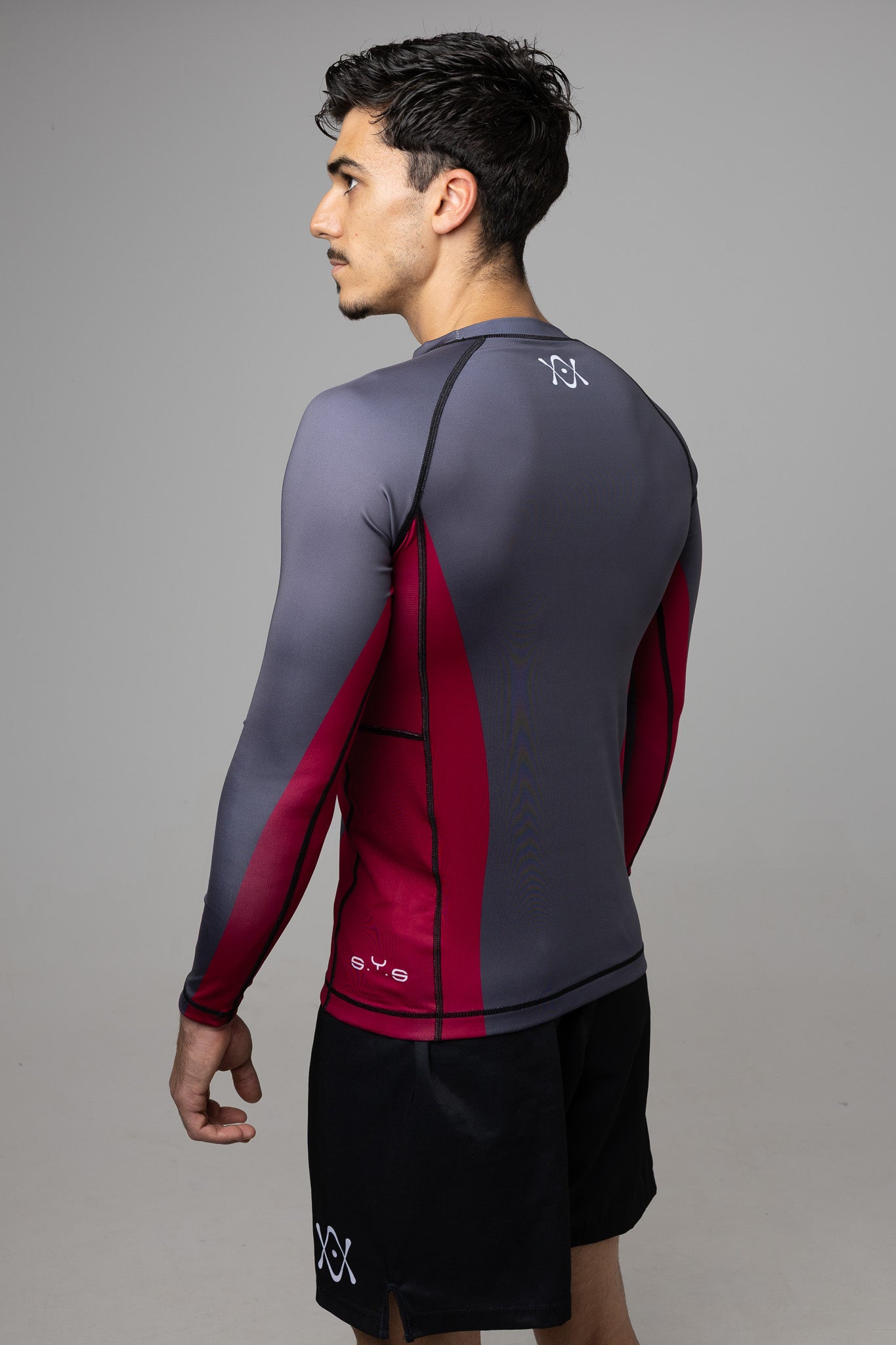 Hombre de espaldas con rashguard gris de manga larga y paneles laterales