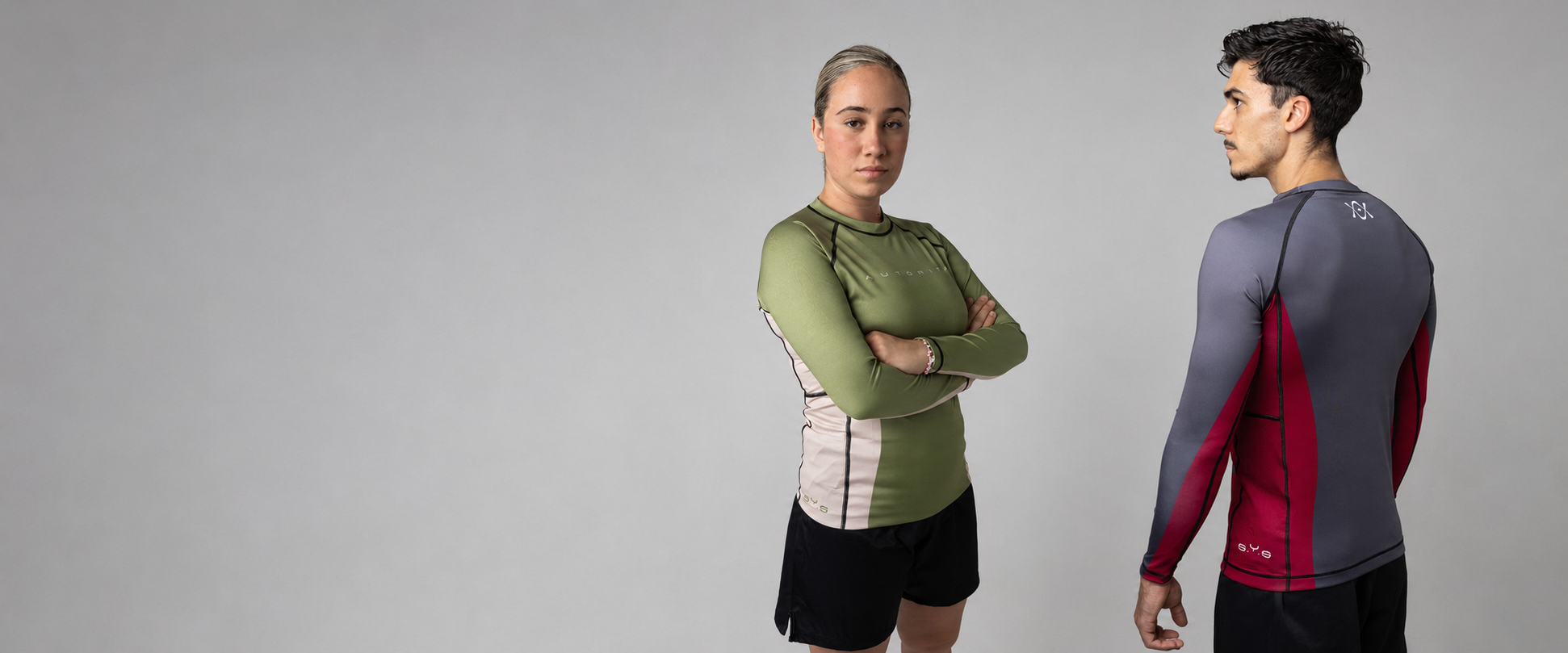 Dos atletas con rashguards de manga larga Autorita verde y gris, licras anti-pilling para BJJ, nogi y grappling con mayor protección.