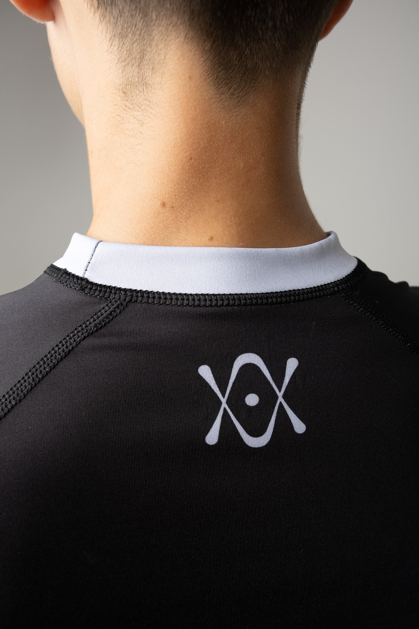 Detalle del logo AUTŌRITA en la espalda de una rashguard negra kids para Brazilian Jiu-Jitsu.
