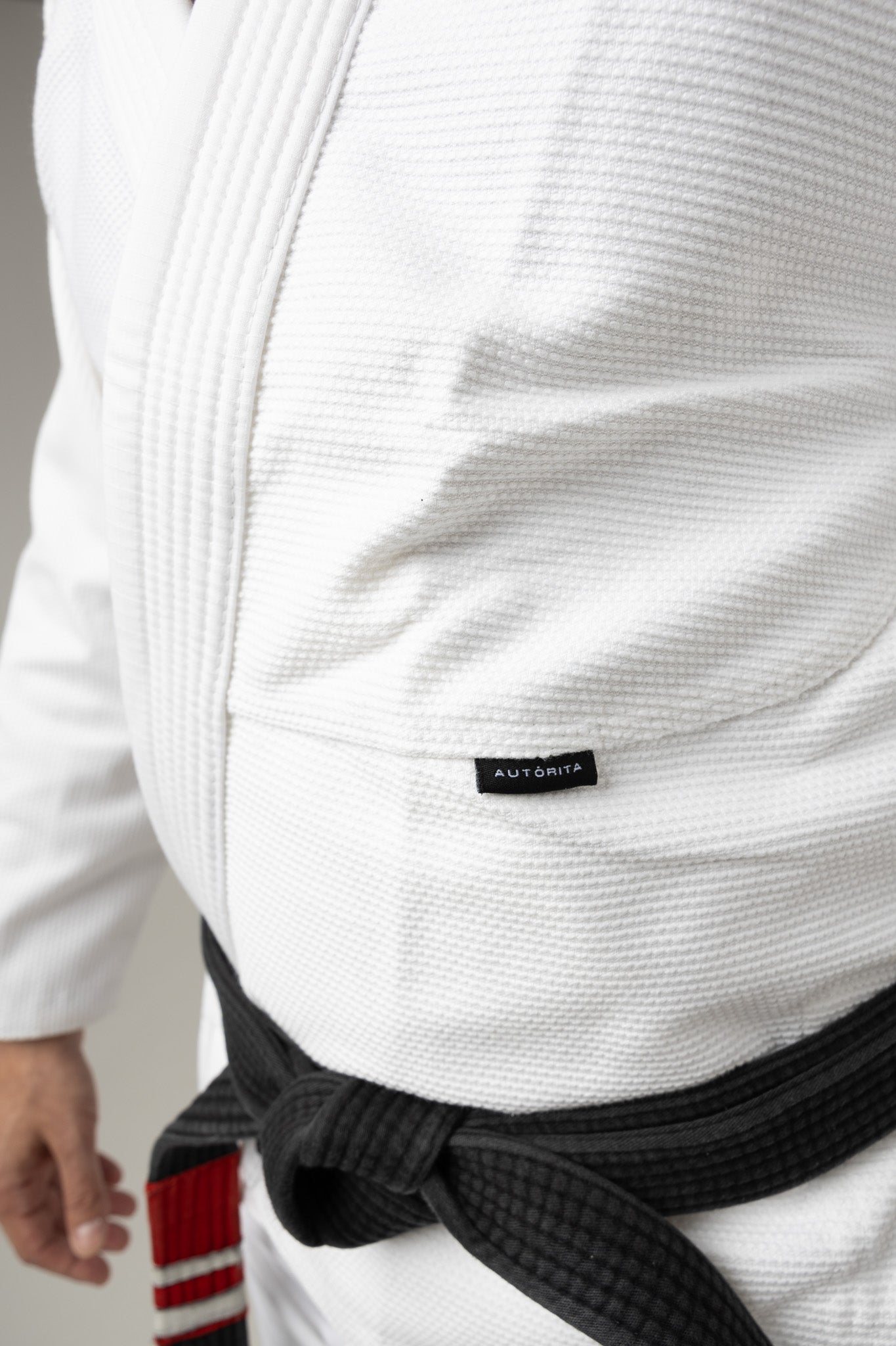 Detalle lateral de la chaqueta del kimono BJJ blanco AUTŌRITA Galea, diseño técnico y premium