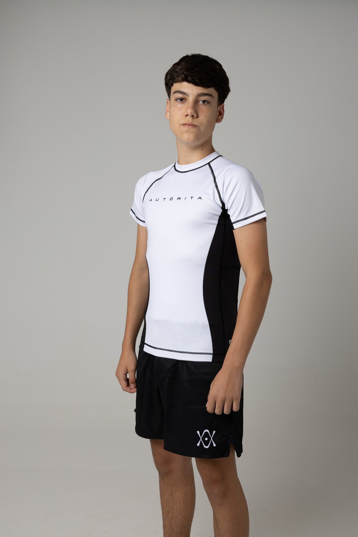 Rashguard blanca infantil AUTŌRITA para BJJ y grappling, diseño minimalista en blanco y negro