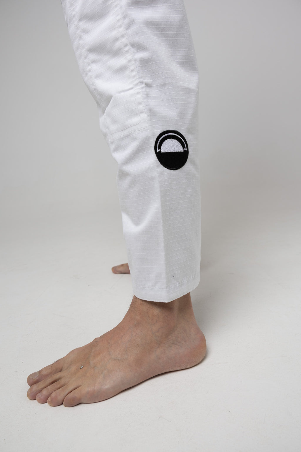 Parche circular en el pantalón del gi BJJ blanco AUTŌRITA Galea, detalle técnico y elegante