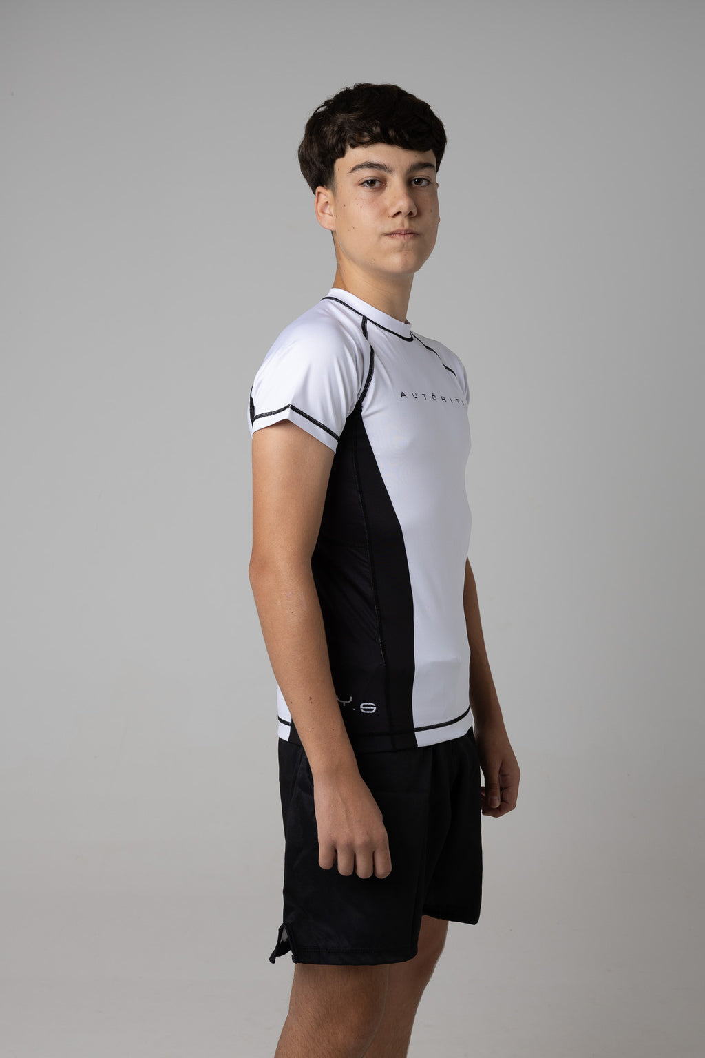 Rashguard kids blanca AUTŌRITA con costuras negras y ajuste deportivo para grappling y competición