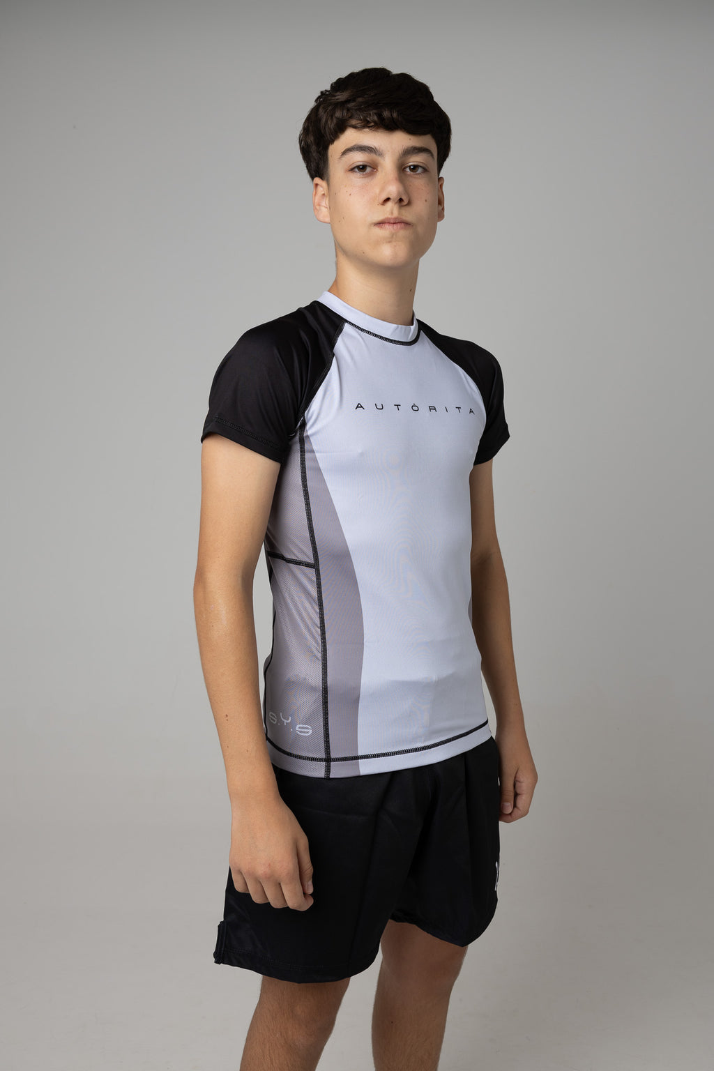 Vista lateral de rashguard gris y negra AUTŌRITA juvenil para BJJ y entrenamiento.