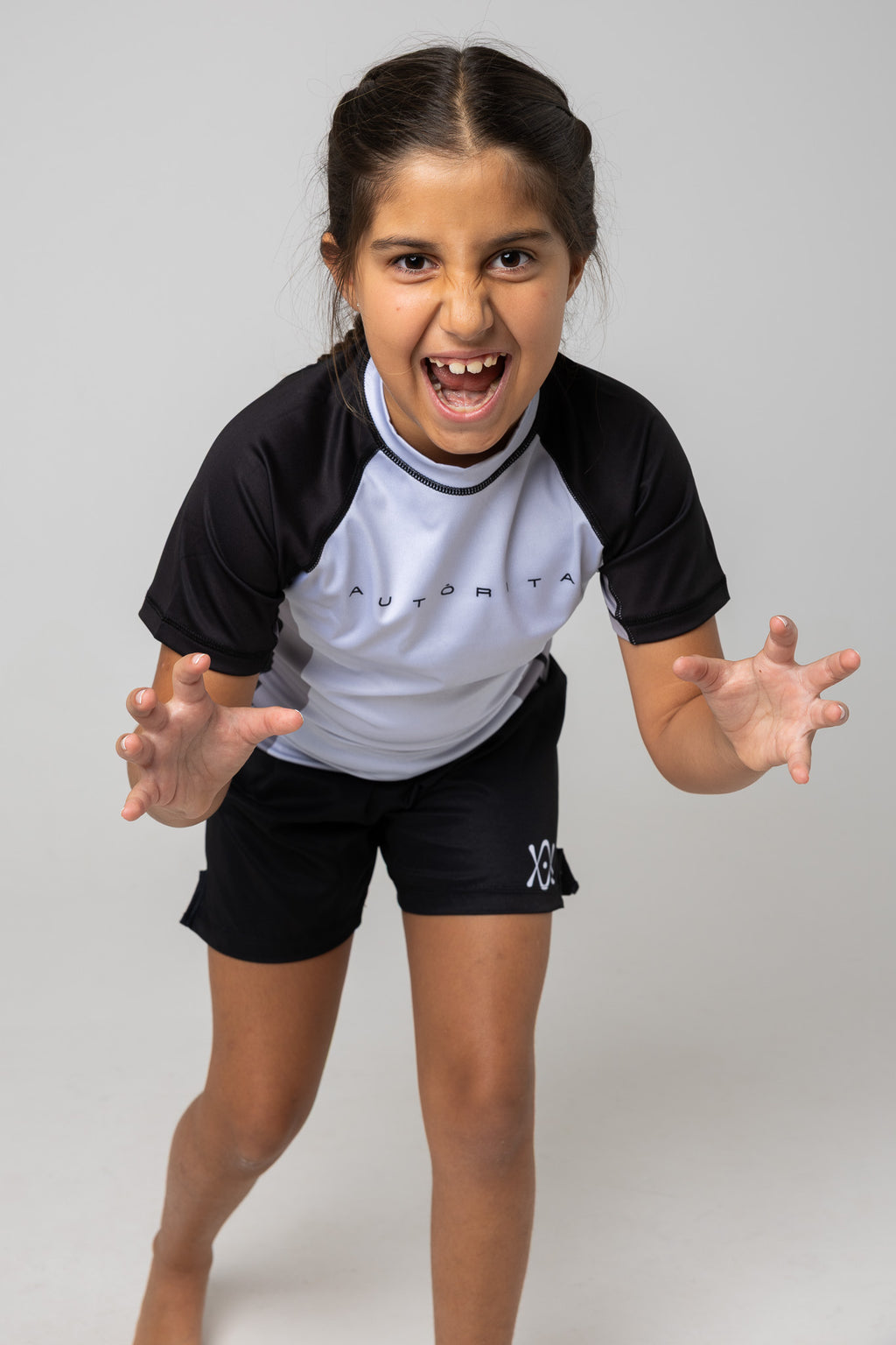 Rashguard gris y negra AUTŌRITA kids para jiu-jitsu en pose de acción.