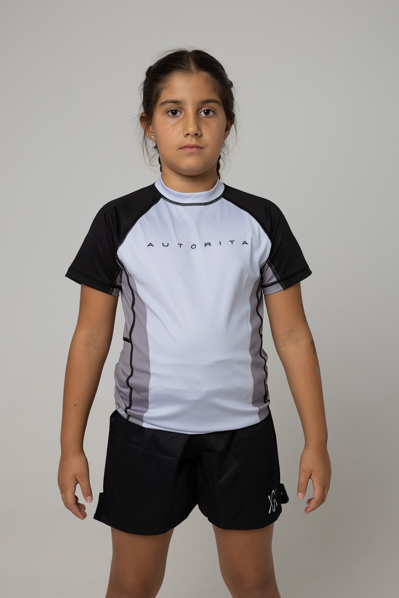 Vista frontal de rashguard gris y negra AUTŌRITA kids para BJJ y grappling.