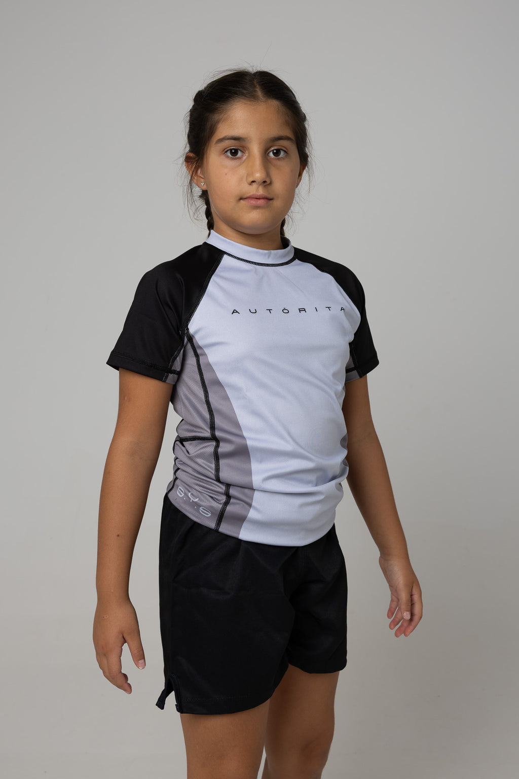 Vista lateral de licra gris y negra AUTŌRITA infantil para Brazilian Jiu-Jitsu.