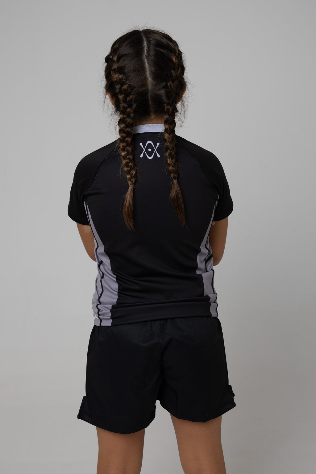 Vista trasera de rashguard negra y gris AUTŌRITA kids con logo en la espalda.