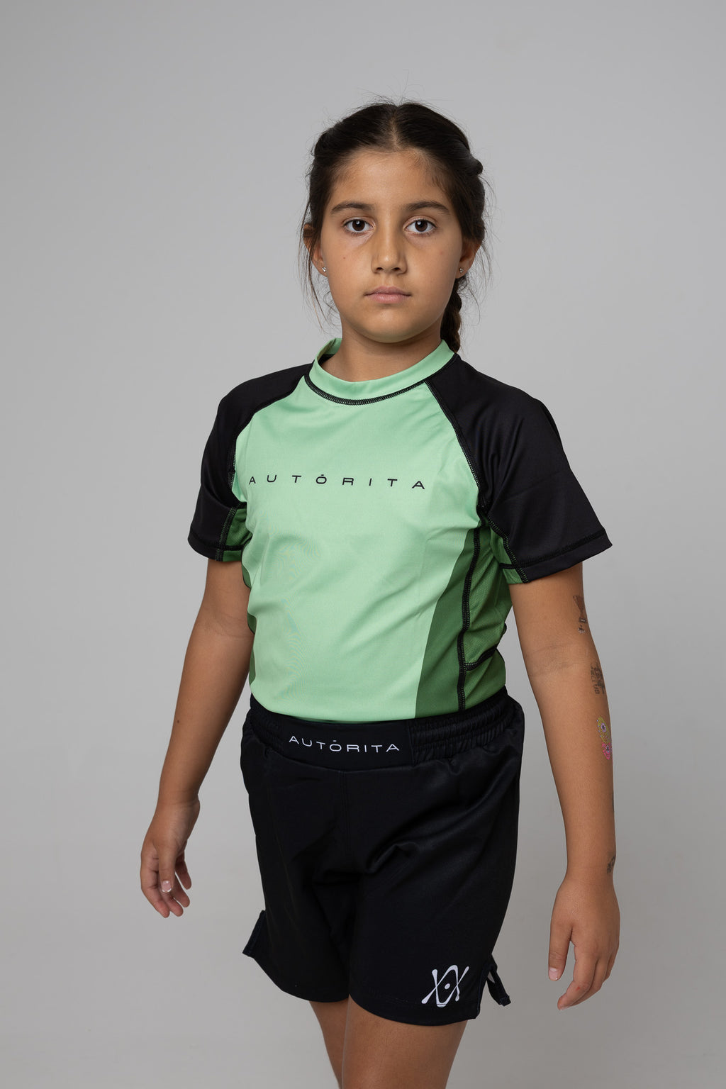 Rashguard verde AUTŌRITA kids para Brazilian Jiu-Jitsu, vista tres cuartos en estudio.