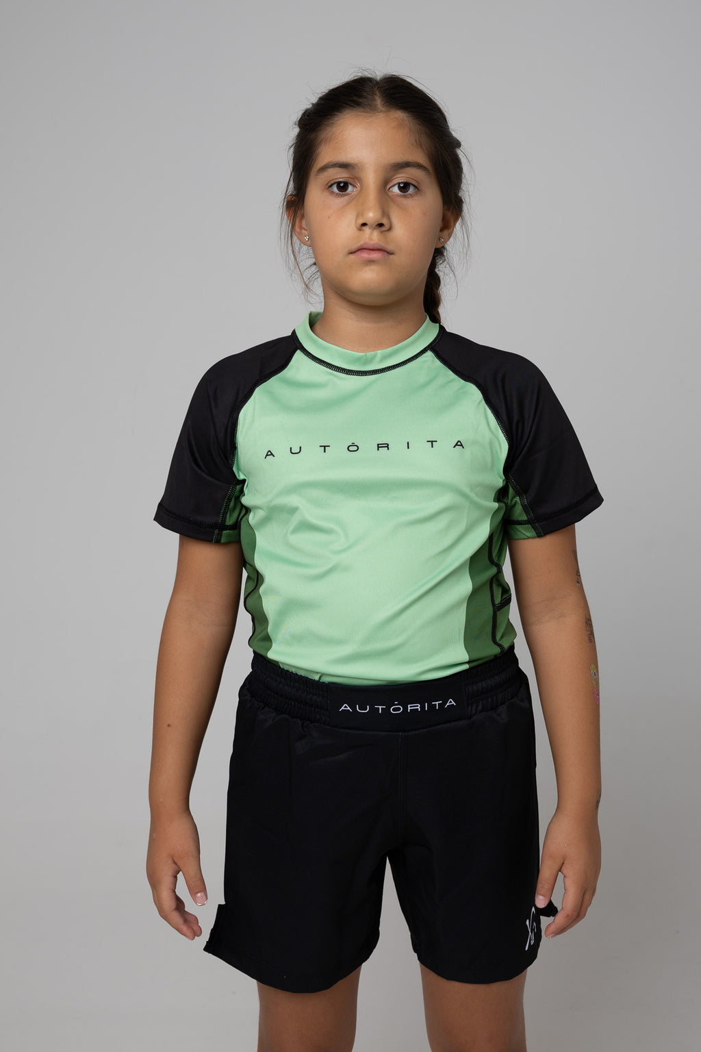 Vista frontal de rashguard verde AUTŌRITA kids para Brazilian Jiu-Jitsu y grappling.